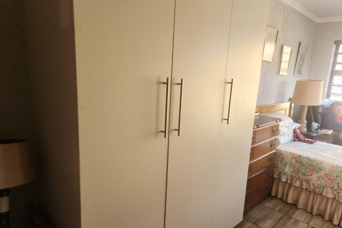 A bedroom featuring a large built-in wardrobe with modern handles and tiled flooring.