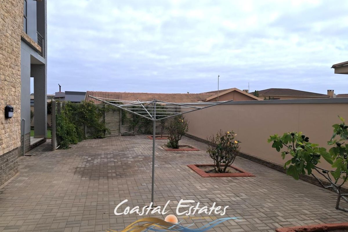 A paved rear courtyard featuring a boundary wall and established garden beds, providing a functional outdoor space.
