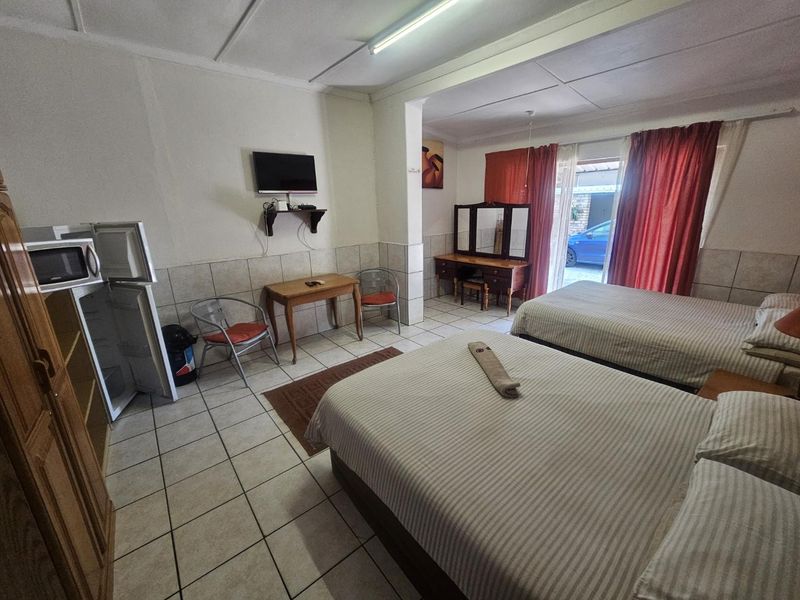 Spacious bedroom featuring ceramic floor tiles, tiled wall wainscoting, and direct access to the exterior through a sliding glass door.