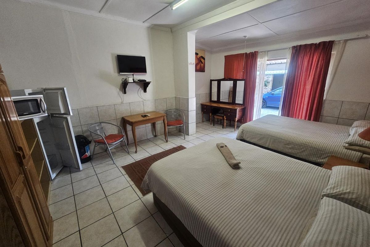Spacious bedroom featuring ceramic floor tiles, tiled wall wainscoting, and direct access to the exterior through a sliding glass door.