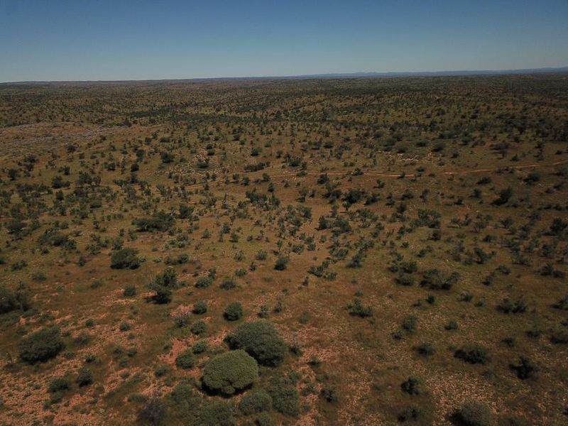 An aerial view of expansive, undeveloped residential land featuring native scrub vegetation and natural terrain.