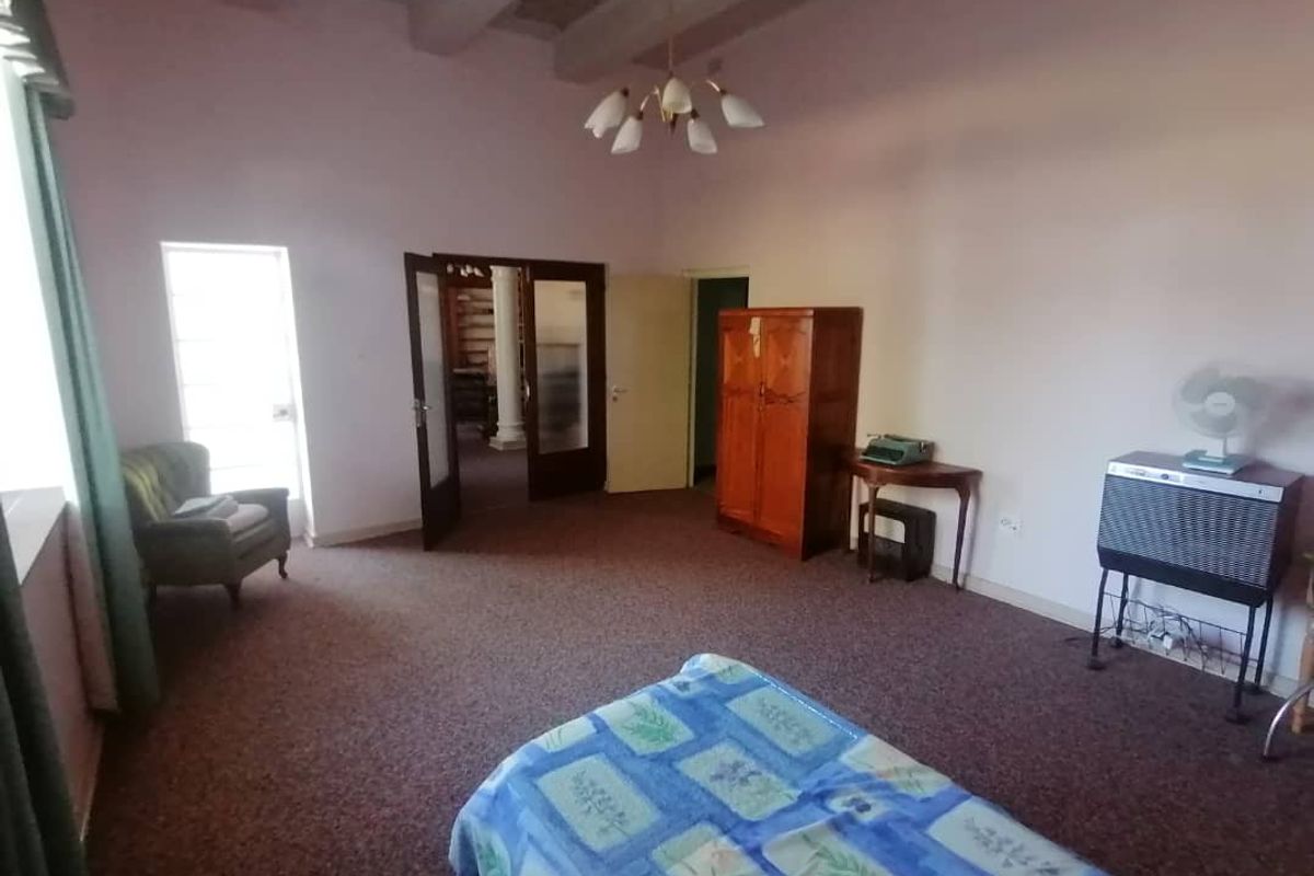 Spacious bedroom featuring exposed ceiling beams, large windows, and double door access to the hallway.
