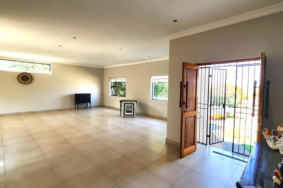 Spacious, open-plan living area featuring neutral tiled flooring, recessed lighting, and direct access to the exterior through a secure timber entrance door.