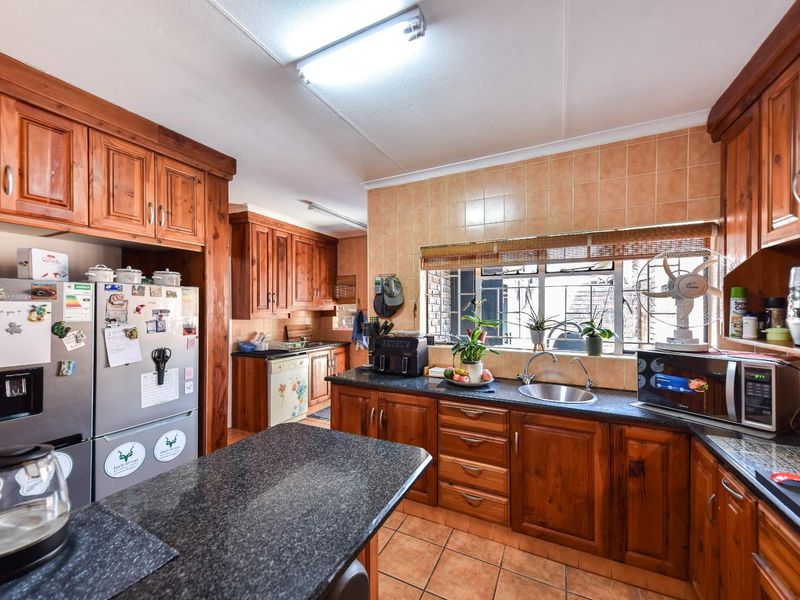 A functional kitchen featuring solid wood cabinetry, granite countertops, tiled backsplash, and tiled flooring, offering a traditional aesthetic with ample storage space.