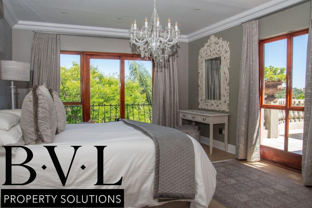 Spacious bedroom featuring elegant crown molding, large wooden-framed glass doors leading to a balcony, and recessed ceiling lighting.