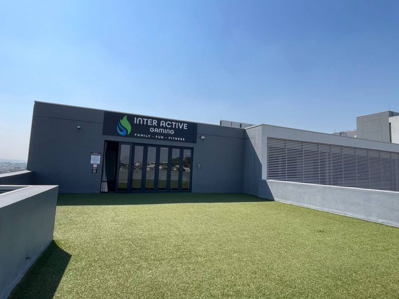 A spacious rooftop terrace featuring artificial turf, modern folding glass doors, and a clean, contemporary exterior finish.