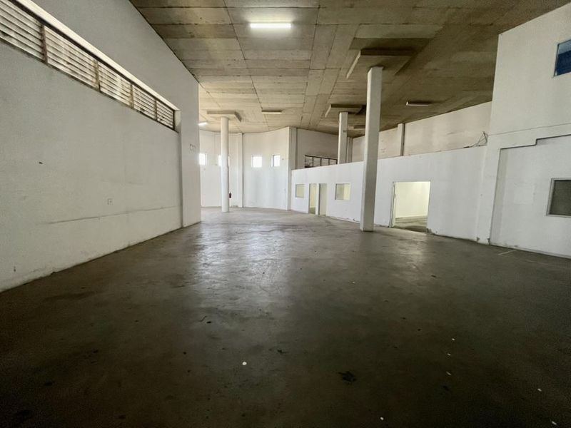 Spacious industrial utility area featuring high concrete ceilings, structural columns, and durable concrete flooring, suitable for warehouse or workshop use.