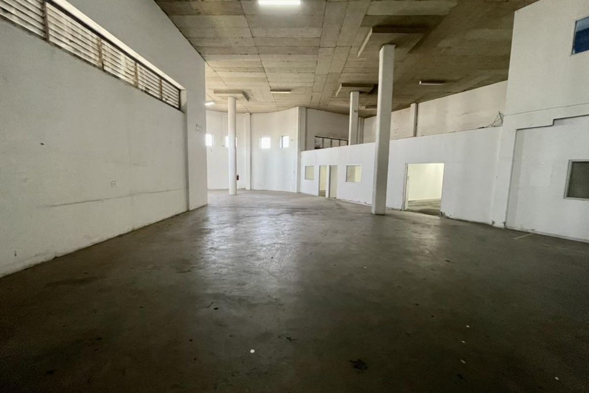 Spacious industrial utility area featuring high concrete ceilings, structural columns, and durable concrete flooring, suitable for warehouse or workshop use.