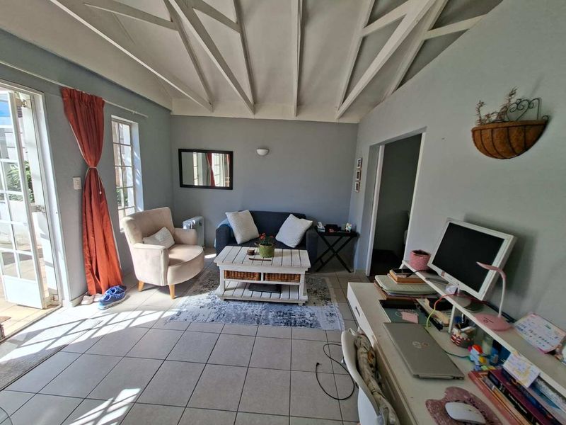 A cozy living room featuring an exposed beam ceiling, tiled flooring, and direct access to an outdoor patio area.
