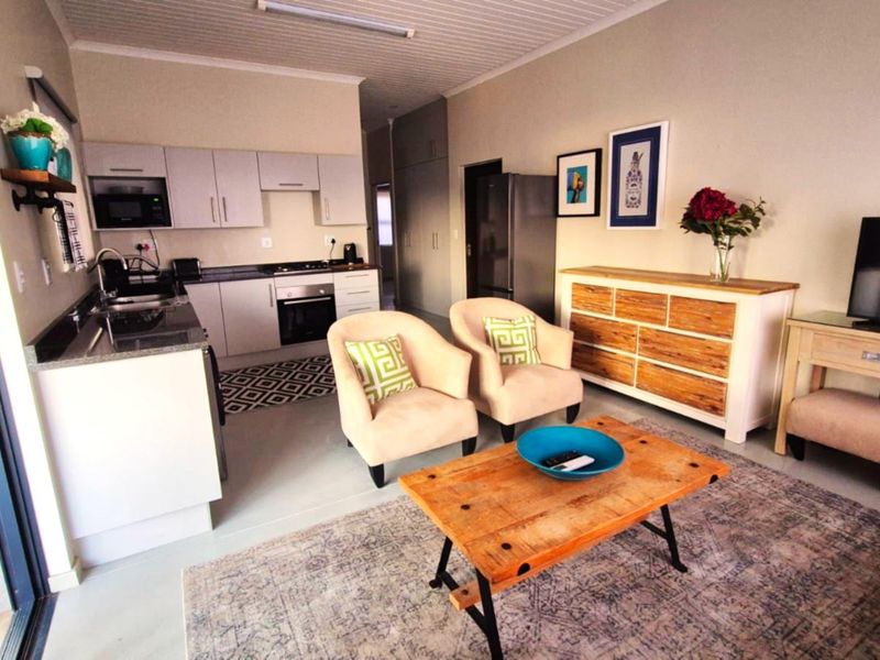An open-plan living area featuring a modern kitchen with built-in appliances, tiled flooring, and direct access to an outdoor space via sliding glass doors.