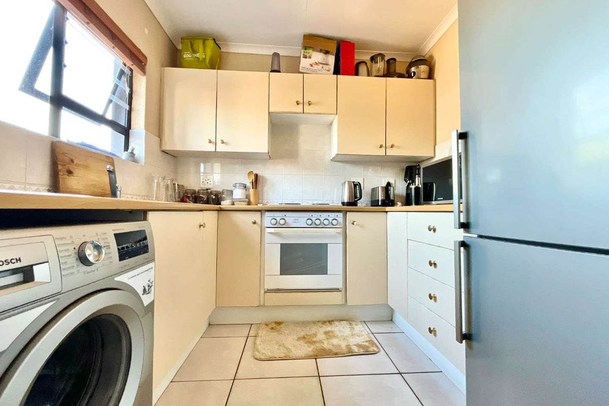 A compact kitchen featuring built-in cabinetry, tiled flooring, a built-in oven, and a hob with a tiled backsplash.
