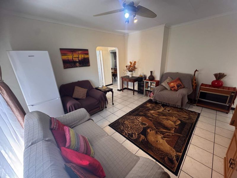 A living room featuring ceramic floor tiles, a ceiling fan, and an arched doorway leading to adjacent living spaces.