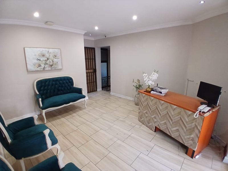 A bright and welcoming reception area featuring neutral walls, modern tiled flooring, and recessed downlighting, providing a professional entry space for the business.
