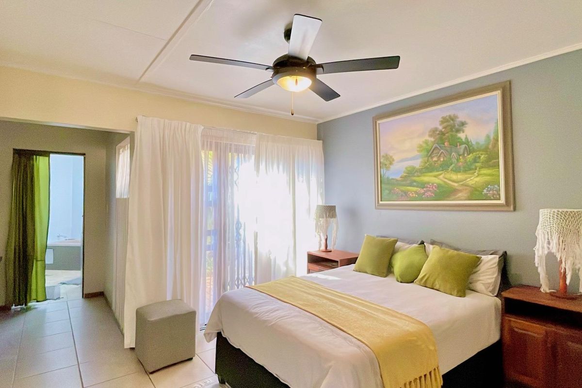 A bedroom featuring a ceiling fan, built-in cupboards, and sliding glass doors providing access to an outdoor area.