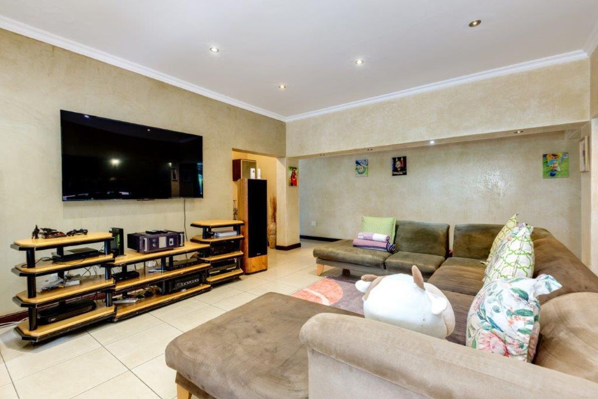 A spacious living room featuring tiled flooring, recessed downlighting, and decorative coving, providing a comfortable area for relaxation and entertainment.