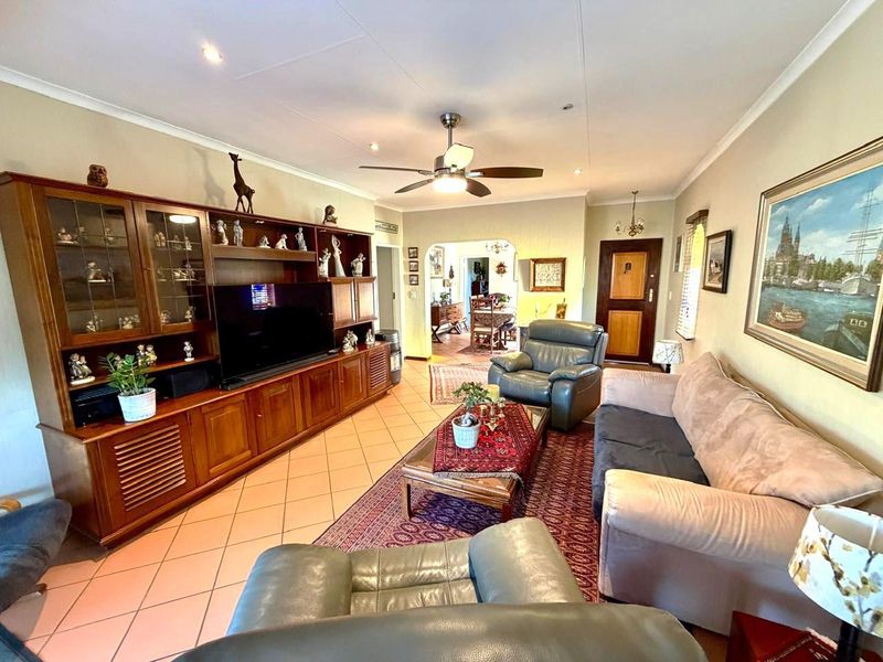 Spacious living room featuring tiled flooring, a ceiling fan, and an open archway leading to the dining area.