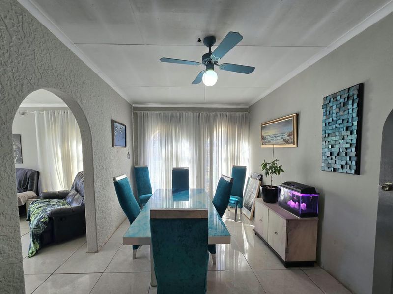 A dining room featuring tiled flooring, a ceiling fan, and an arched entryway leading to an adjacent living space.