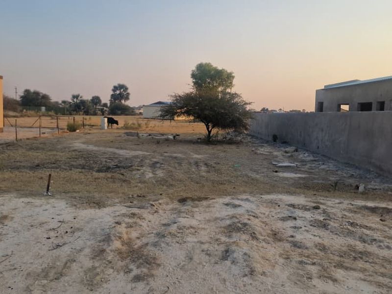 A view of a vacant residential plot featuring boundary walls and fencing, showing undeveloped land ready for construction.