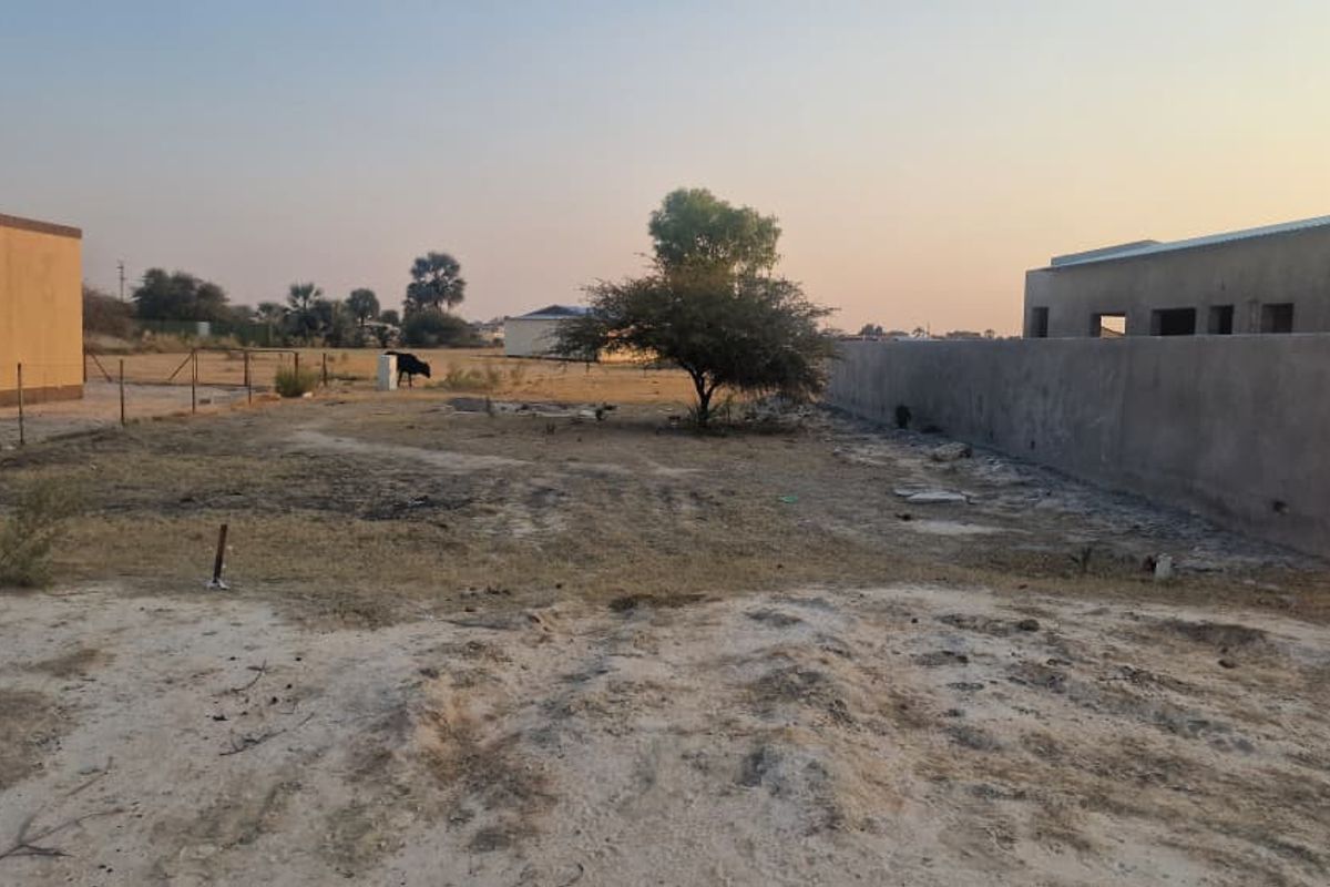 A view of a vacant residential plot featuring boundary walls and fencing, showing undeveloped land ready for construction.