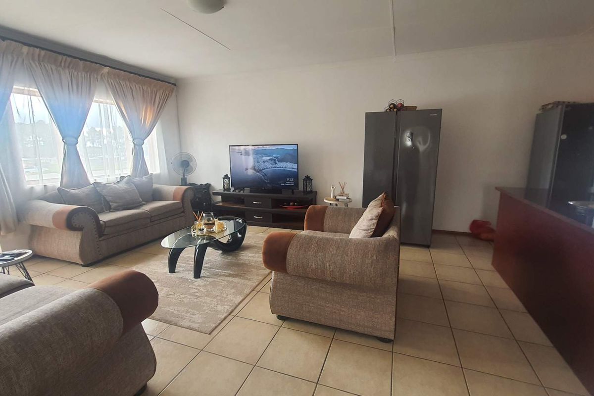 A spacious living room featuring neutral tiled flooring and a large window, providing a comfortable and functional area for relaxation.