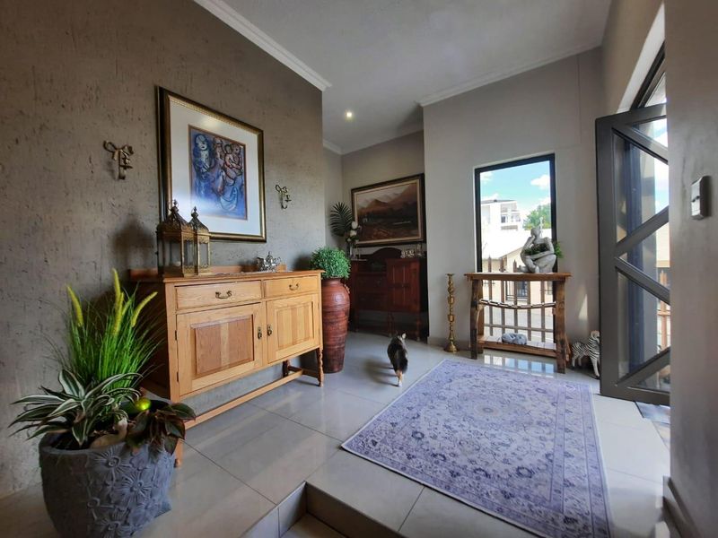 A welcoming entrance hall featuring neutral tiled flooring, modern recessed lighting, and a large glass door that allows for ample natural light.