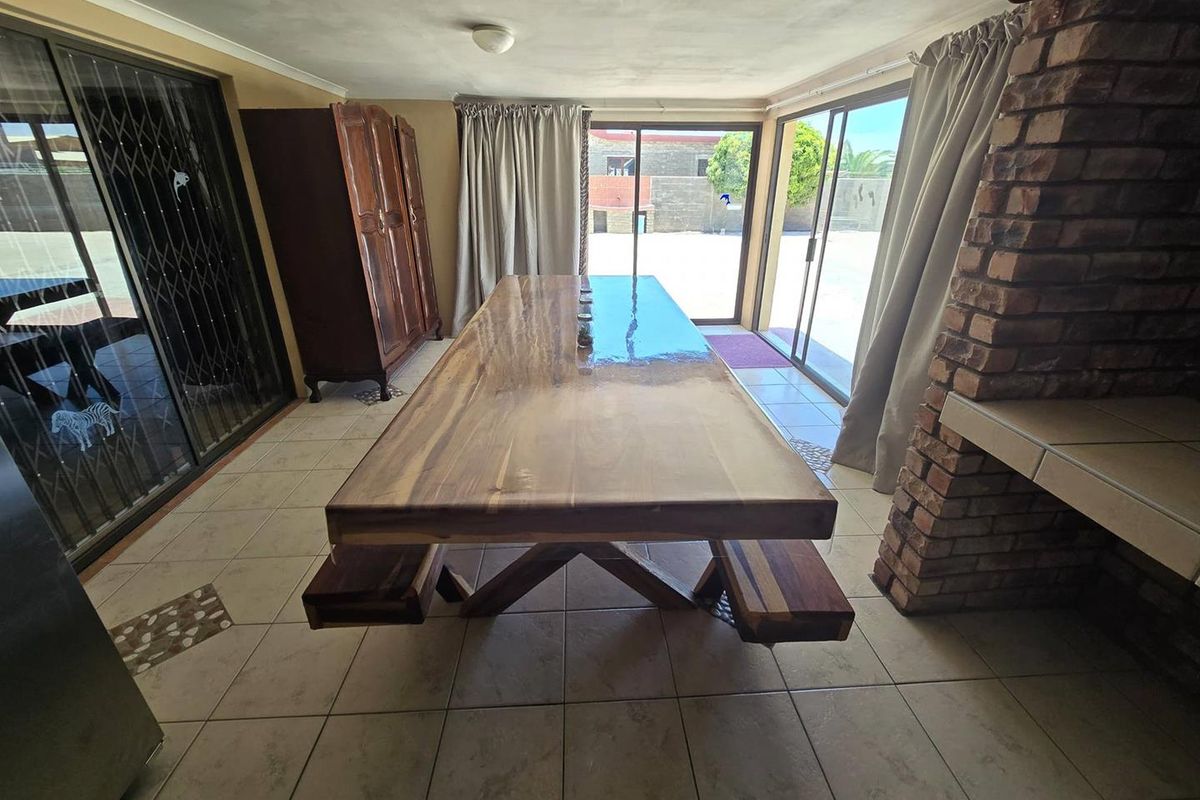 Spacious indoor entertainment area featuring a built-in brick fireplace, tiled flooring, and large sliding glass doors providing direct access to the rear garden.