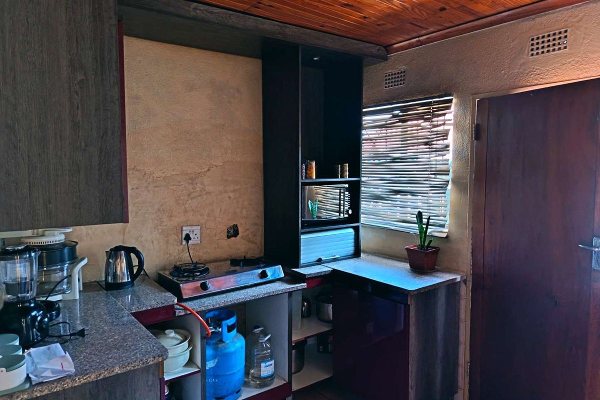 A compact kitchen featuring granite countertops, a gas hob, and timber ceiling, currently requiring cosmetic updates and improved finishings.
