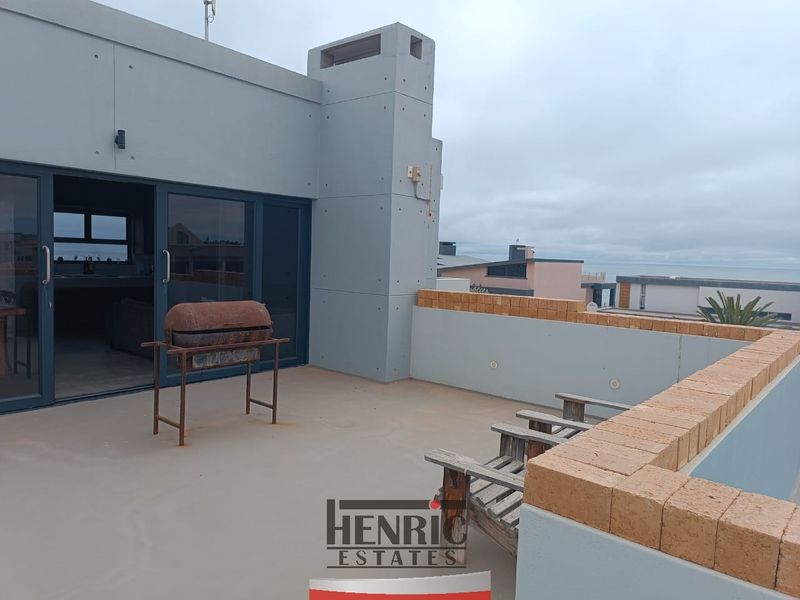Spacious outdoor balcony featuring a concrete chimney stack, brick parapet wall, and sliding glass doors leading into the interior living space.