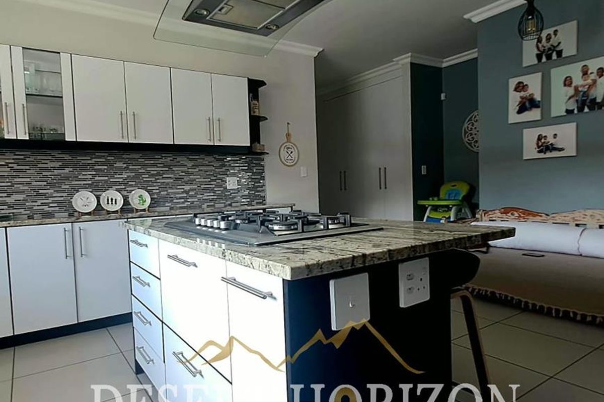 Modern kitchen featuring a central island with a gas hob, extractor fan, granite countertops, and ample built-in cabinetry.