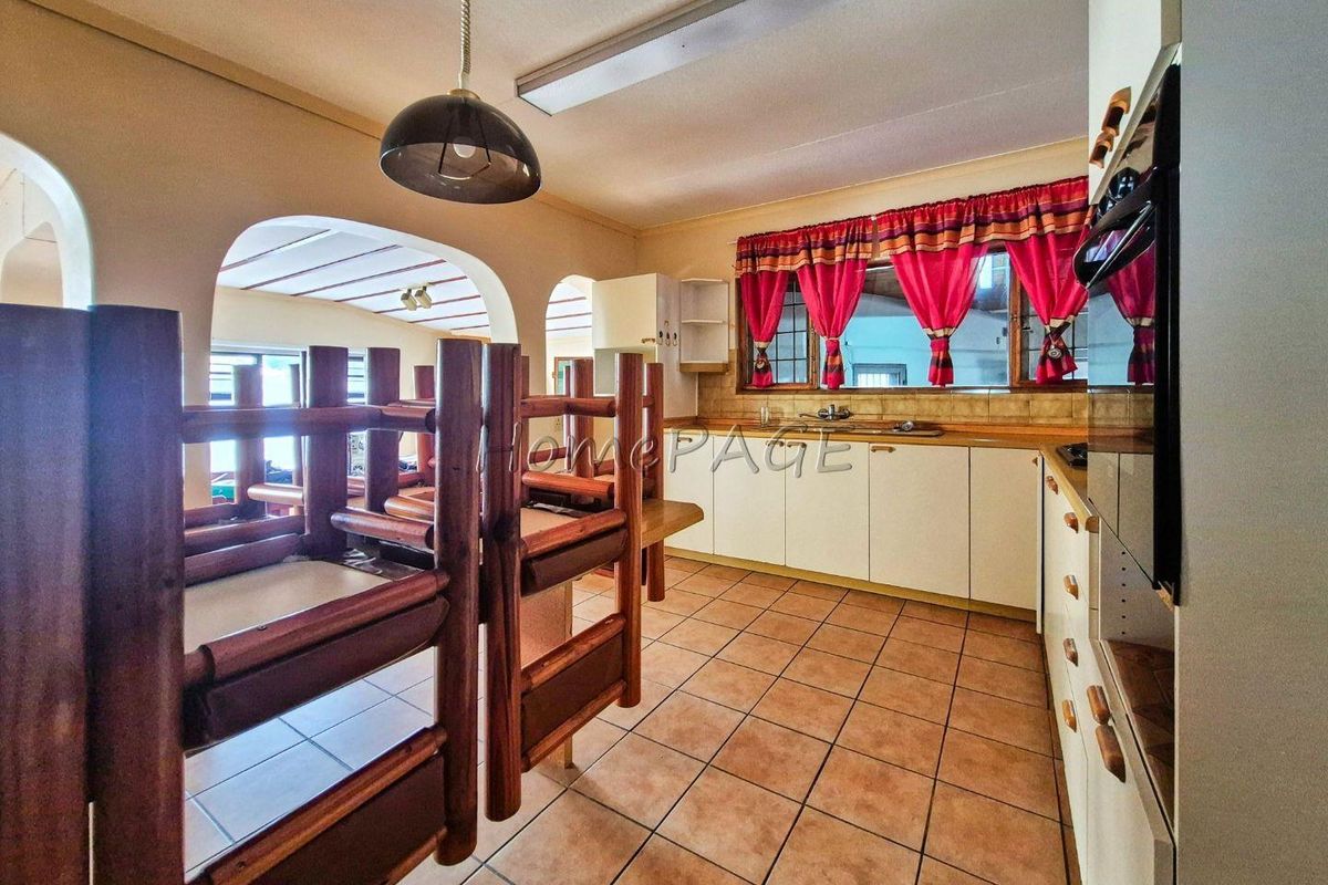 A functional kitchen featuring tiled flooring, built-in cabinetry, and a built-in oven, connected to the living area via an open archway.