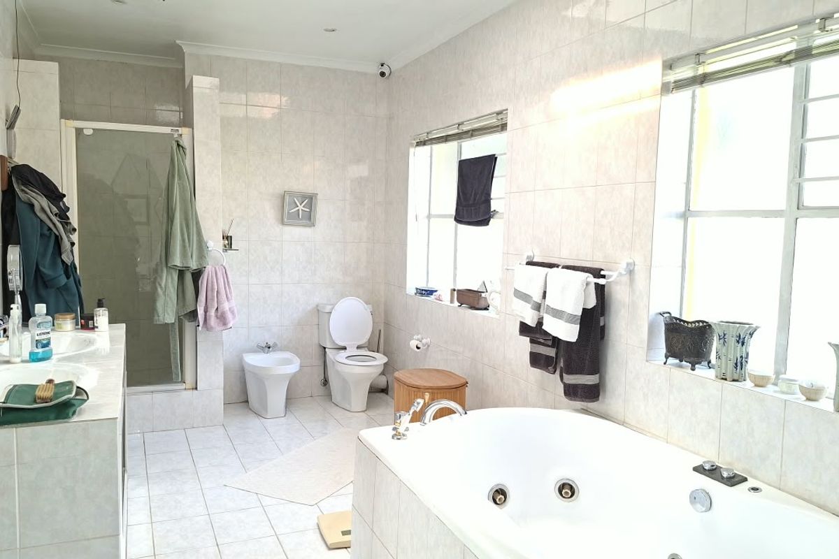 Spacious bathroom featuring a built-in jetted bathtub, separate shower enclosure, bidet, toilet, and a double vanity with tiled finishes throughout.