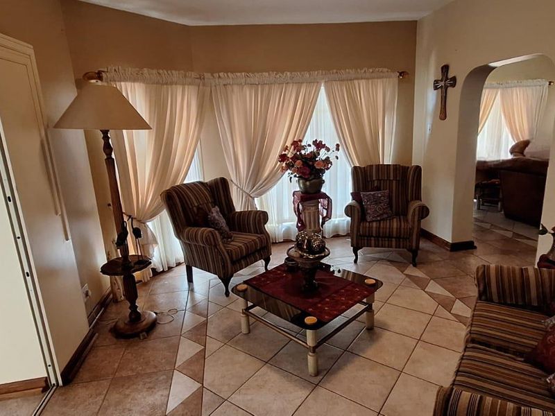 A cozy living room featuring tiled flooring, an arched entryway, and a bay window that allows for natural light.