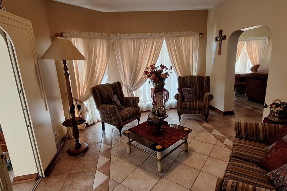 A cozy living room featuring tiled flooring, an arched entryway, and a bay window that allows for natural light.