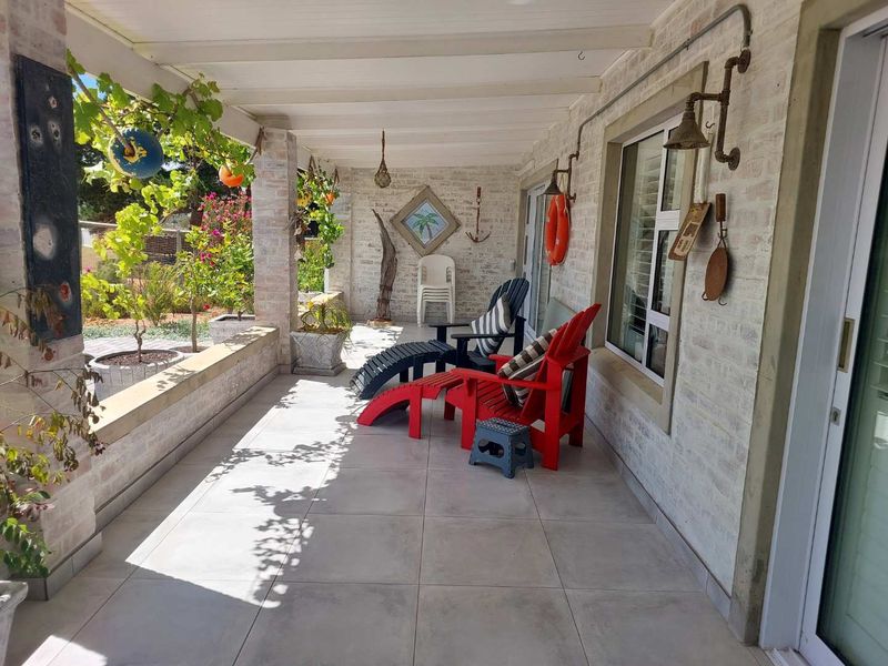 A covered patio area featuring tiled flooring, exposed brick walls, and direct access to the garden through sliding glass doors.