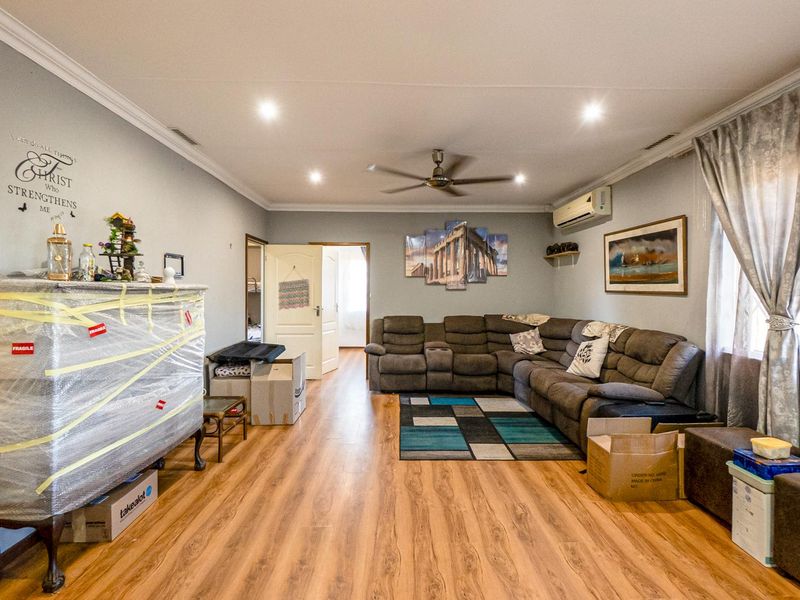 Spacious living room featuring laminate flooring, recessed downlighting, a ceiling fan, and a wall-mounted split-system air conditioner.