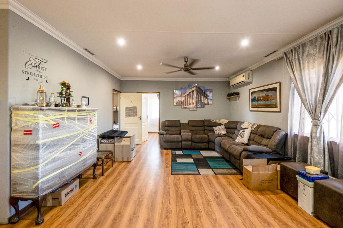 Spacious living room featuring laminate flooring, recessed downlighting, a ceiling fan, and a wall-mounted split-system air conditioner.