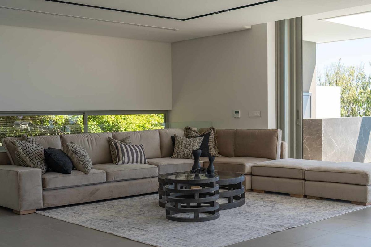 Modern living room featuring large sliding glass doors, sleek tiled flooring, and recessed ceiling lighting, creating a bright and open atmosphere.