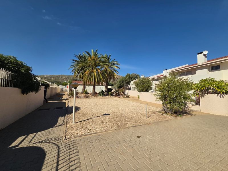A spacious rear courtyard area featuring paved sections, gravel landscaping, and boundary walls, providing a low-maintenance outdoor space for the townhouse.
