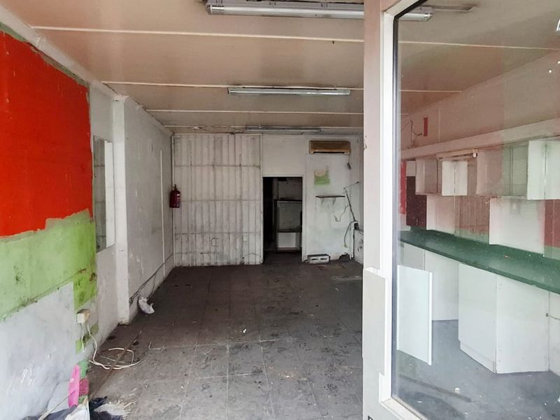 Vacant commercial open-plan space featuring built-in cabinetry, tiled flooring, and fluorescent lighting, requiring refurbishment to restore its functional appeal.