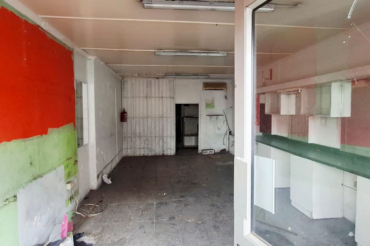 Vacant commercial open-plan space featuring built-in cabinetry, tiled flooring, and fluorescent lighting, requiring refurbishment to restore its functional appeal.