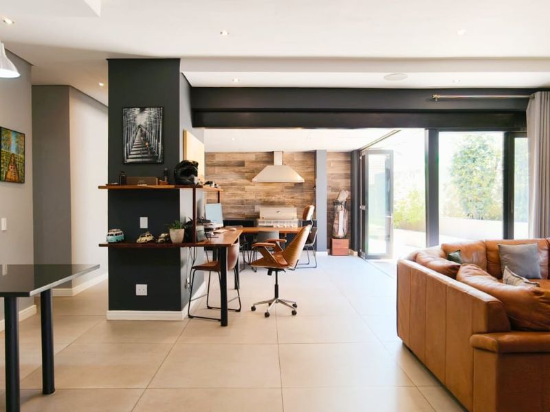 Spacious open-plan living area featuring large format floor tiles, recessed lighting, and seamless flow to the outdoor space through wide sliding glass doors.