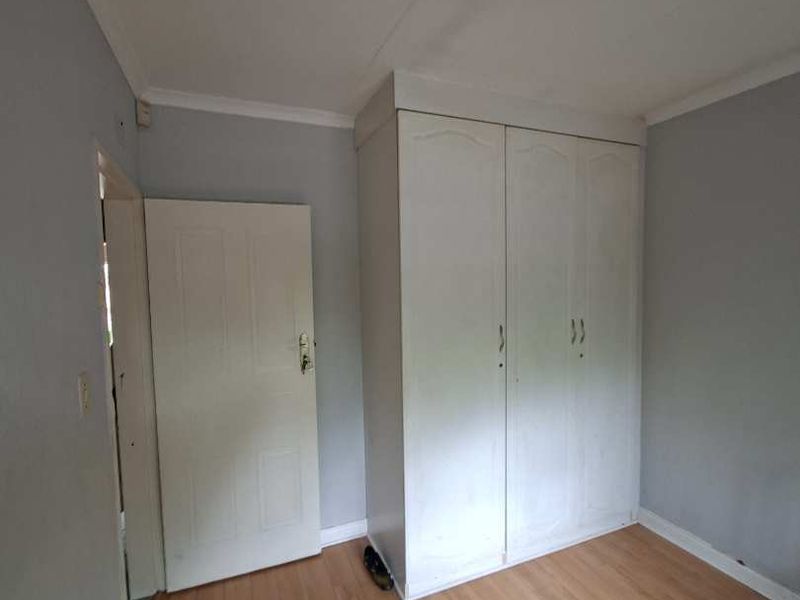 A simple, empty bedroom featuring light-toned laminate flooring and a built-in wardrobe, offering a clean canvas for personalization.