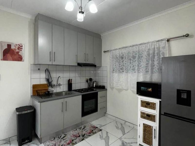 A modern kitchen featuring grey cabinetry, built-in oven, gas hob, extractor fan, and stylish marble-look floor tiles.