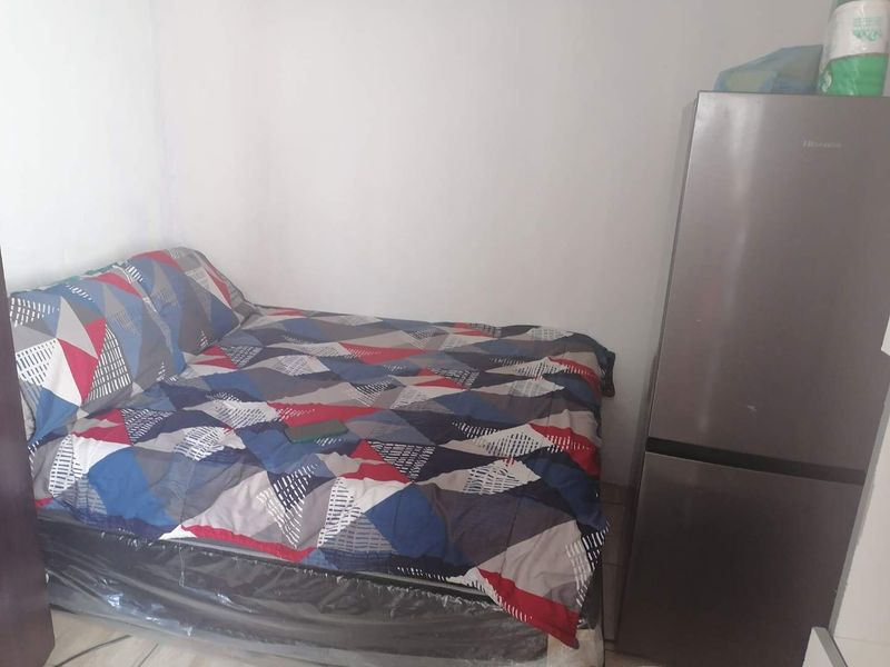 A small bedroom space featuring plain walls and tiled flooring.