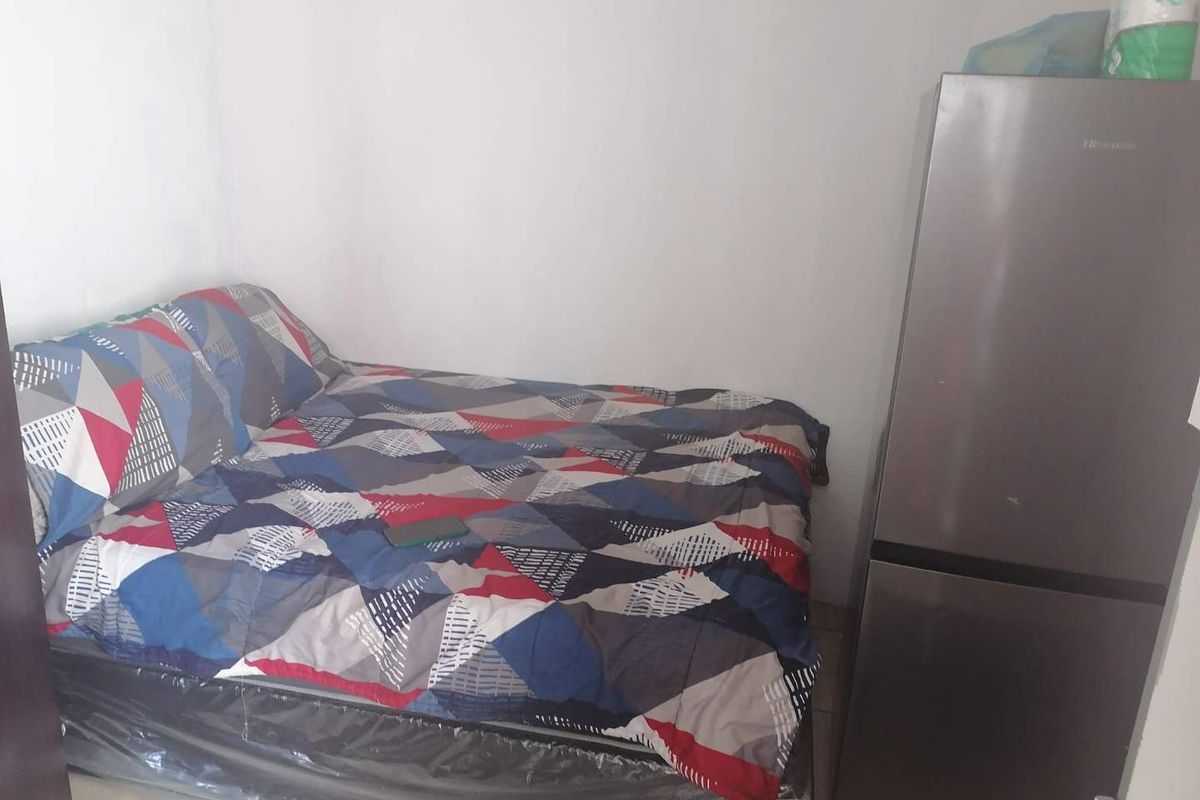 A small bedroom space featuring plain walls and tiled flooring.
