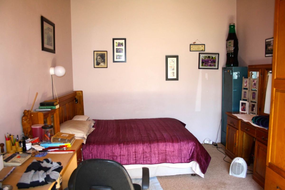 A functional bedroom featuring neutral wall tones and carpeted flooring, providing a comfortable and practical living space.