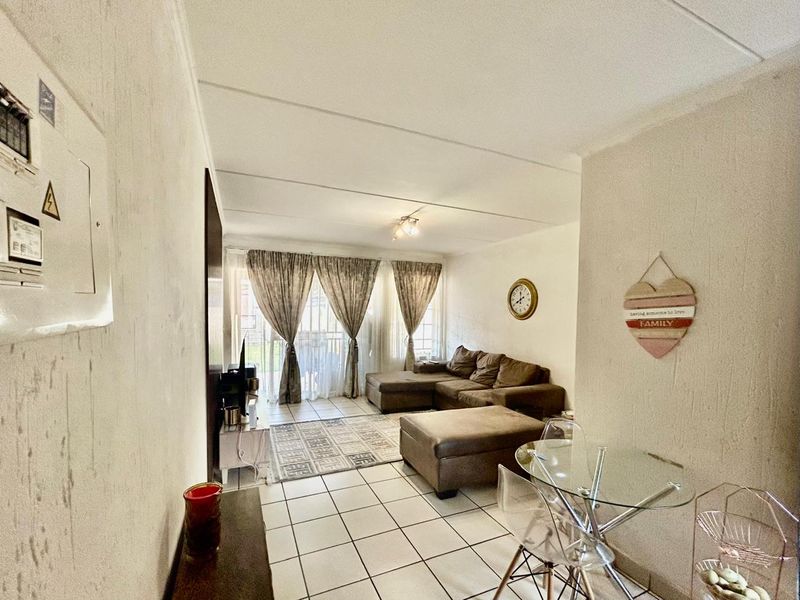 Open-plan living area featuring tiled flooring and a sliding glass door leading to an outdoor space, with an integrated electrical distribution board.