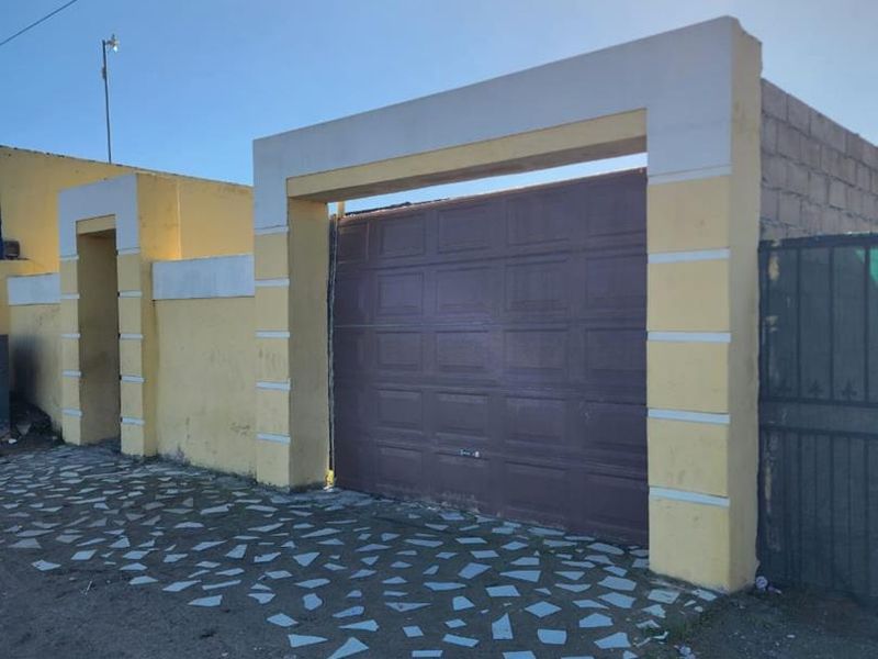 Exterior view of a residential garage featuring a sectional door and masonry boundary wall with a paved driveway area.