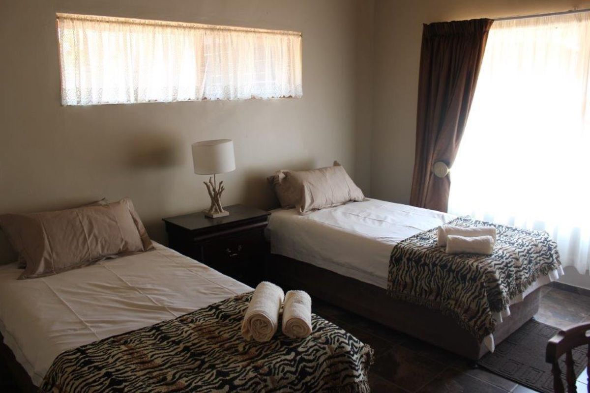 A functional bedroom featuring tiled flooring and natural light through a horizontal window and standard window, suitable for guest accommodation.