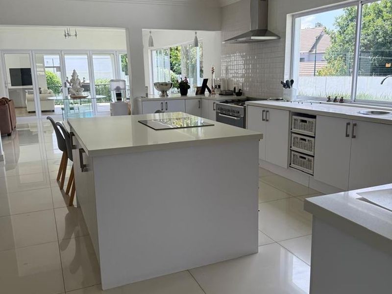 Modern, bright kitchen featuring a central island, quartz countertops, subway tile backsplash, and high-quality stainless steel appliances, flowing into an open-plan living area.